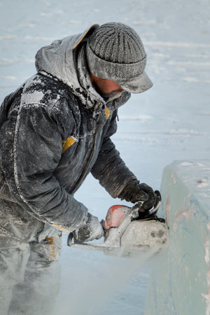 Portrait of a working assembler in a winter jacket and a black cap with a visor near the ice fig-ureの写真素材
