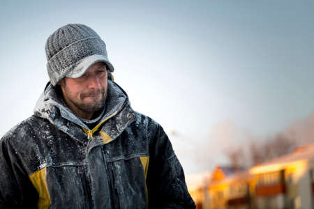 Portrait of a working assembler in a winter jacket and a black cap with a visor near the ice fig-ure