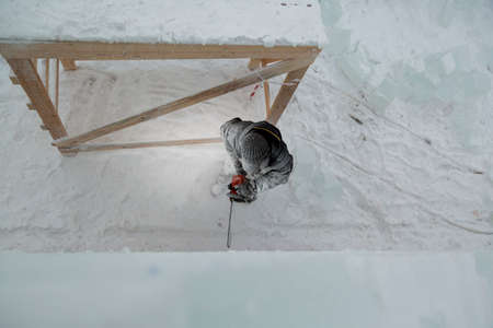 The sculptor cuts out the contours of the future composition with a chainsaw in an ice slab