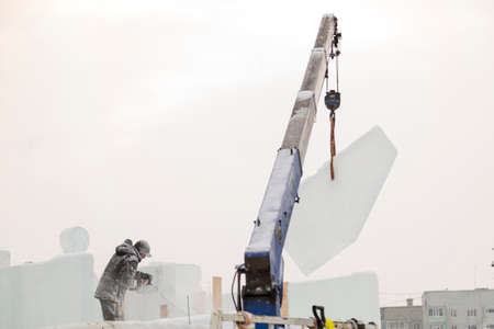 The sculptor cuts out the contours of the future composition with a chainsaw in an ice slab