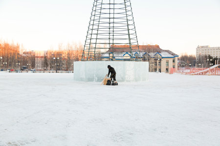A worker in a winter jacket with a hood and a wool knitted cap with a visor at the workplace