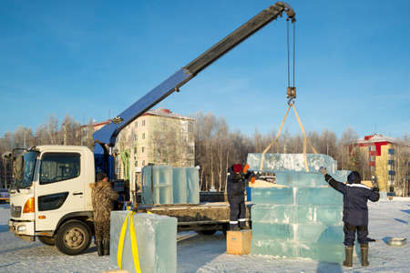 A worker pushes the ice blocks apart with a crowbar