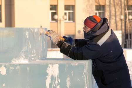 Close-up of a worker in a blue jacket and a knitted hat at the workplaceの写真素材