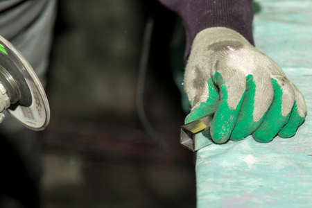 A worker using a grinder processes a metal part