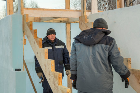 Two workers assemble the slide frame from wooden beams
