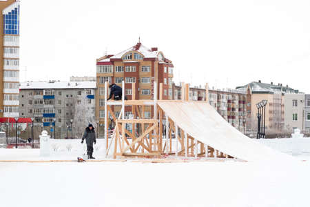 Two workers assemble the slide frame from wooden beamsの写真素材