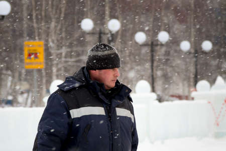 Worker in a jacket with a hood and a woolen knitted hat at the workplace