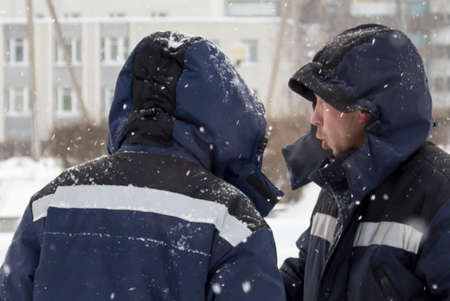 Portrait of a worker in a blue jacket with a hood over his head at a construction site