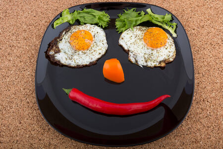 Smiling face made of fried eggs and vegetables on the plateの写真素材