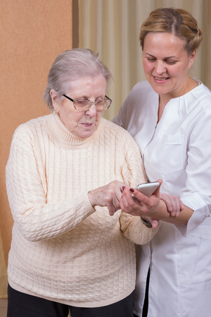 Nurse helping elderly woman with cellphoneの写真素材