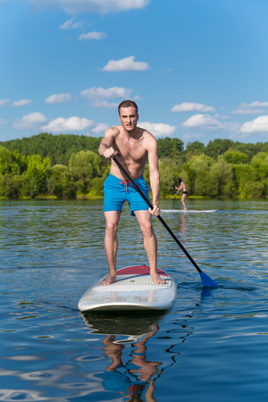 Young attractive man on stand up paddle board in the lake, SUPの写真素材