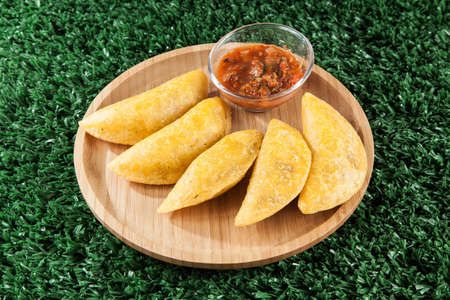 Tasty colombian food, fried empanada; photo on wooden background.