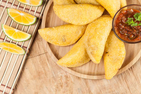 Tasty colombian food, fried empanada; photo on wooden background.