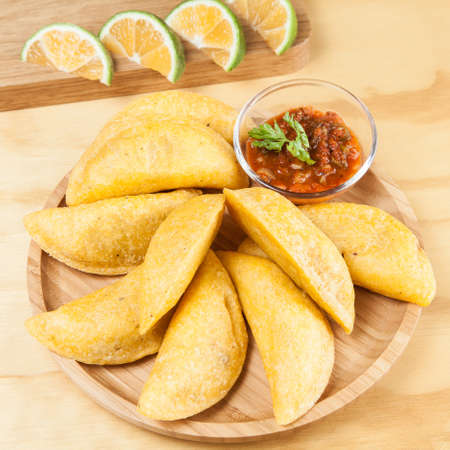 Tasty colombian food, fried empanada; photo on wooden background.