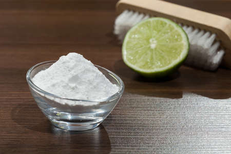 Baking soda - sodium bicarbonate and lemon on the wooden dark.