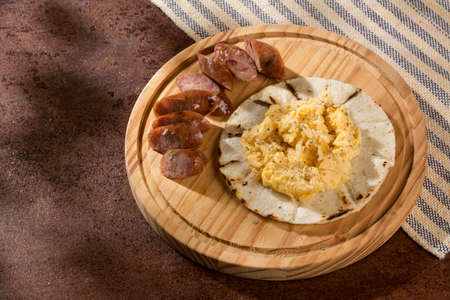Tasty Colombian breakfast; White corn arepa with chorizo and scrambled eggs.の写真素材
