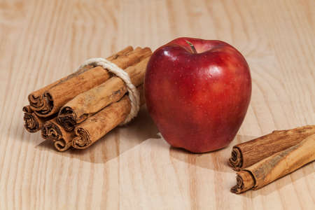Red apple with a cinnamon stick; photo on wooden background.の写真素材