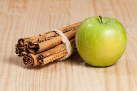 Green apple with a cinnamon stick; photo on wooden background.の写真素材
