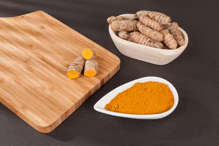 Turmeric - Curcuma longa root and turmeric powder; Photo on dark background.