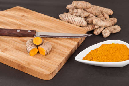 Turmeric - Curcuma longa root and turmeric powder; Photo on dark background.
