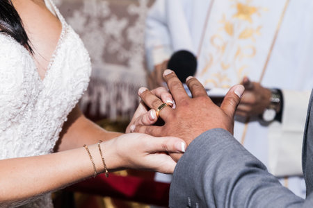 Close up, bride's hands placing wedding ring on her husband on the wedding day.の写真素材