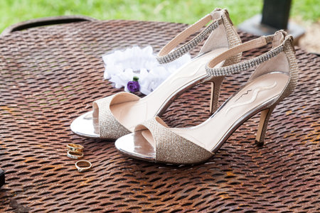 Wedding. Bride accessories: league, wedding rings near bridal shoes on high heelsの写真素材