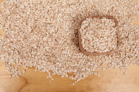 Delicious and healthy cereal - oat flakes on wooden background.