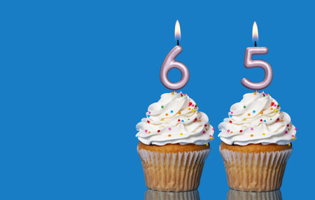 Birthday Cupcakes With Candles Lit Forming The Number 65 - Photo On Blue Background