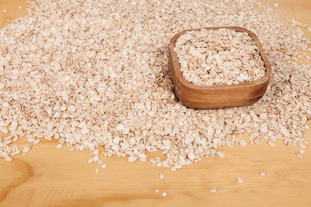 Delicious and healthy cereal - oat flakes on wooden background.