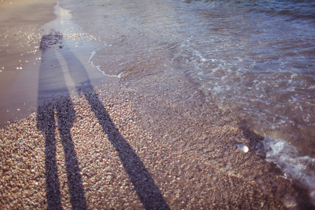Shadows of a couple on the beach, near the waterの写真素材