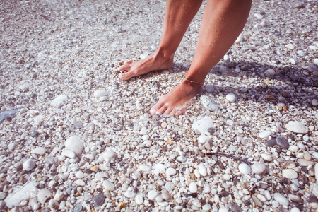 Young woman on the beach collecting pebbles on a glass bottleの写真素材