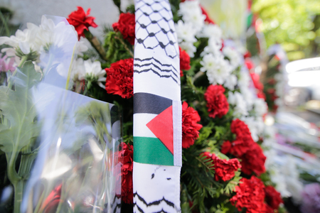 Flowers with the Palestinian flag and candles on the pavementの写真素材