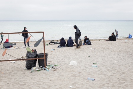 VAMA VECHE, ROMANIA - MAY 1, 2018: Young people rest on the beach amongst debris (especially empty bottles), after partying all night, early in the morning just before sunriseのeditorial素材