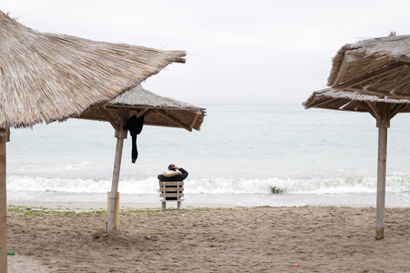 Young man relaxing on the beach after partying all night, early in the morning just before sunrise in the seaside resort of Vama Veche, Romaniaのeditorial素材
