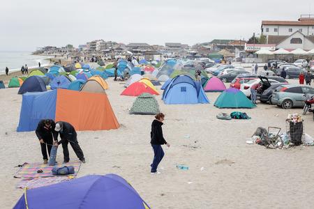 VAMA VECHE, ROMANIA - MAY 1, 2018: Young people rest on the beach amongst debris (especially empty bottles), after partying all night, early in the morning just before sunriseのeditorial素材