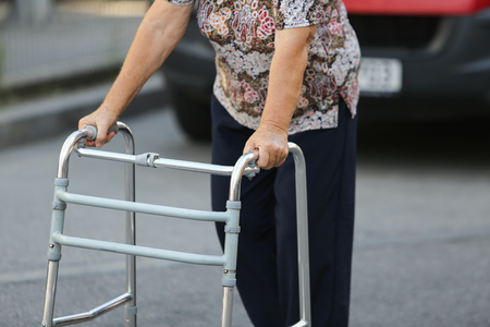 Elderly woman walking with the help of a metal walkerの写真素材