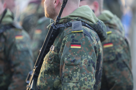Bucharest, Romania - December 1, 2018: Details with the uniform and flag of German soldiers, armed with Heckler & Koch G36 5.56Ã45mm NATO assault rifle, taking part at the Romanian National Day military parade.のeditorial素材