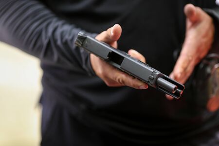 Details with the hands of a man handling a 9mm handgun