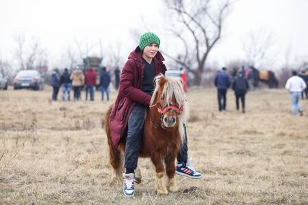 Pietrosani, Romania - January 6, 2019: Young boy is bareback riding a pony before an Epiphany celebration horse race.のeditorial素材