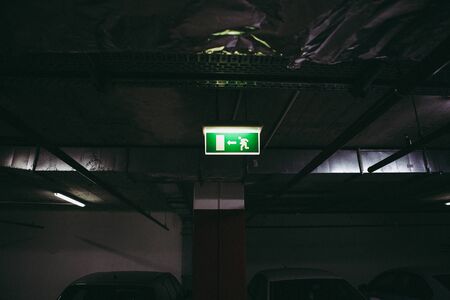 Close up of an exit this way sign inside an underground parking place