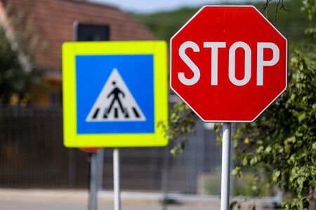 Stop and pedestrian crossing sign one next to another on a street