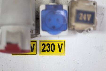 Worn out 400v, 230v and 24 industrial and multiphase power plugs and sockets on a dirty wall inside...