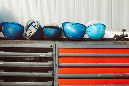 Dirty blue worker helmets on top of an old, rusty and dirty workbench in a workshopの写真素材