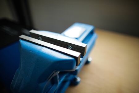 Shallow depth of field image with a heavy iron vice on a workbench inside a workshop with no people aroundの写真素材