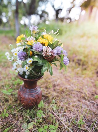 Bouquet of colorful wild wild flowers in a broken clay pot laid on the grassの写真素材