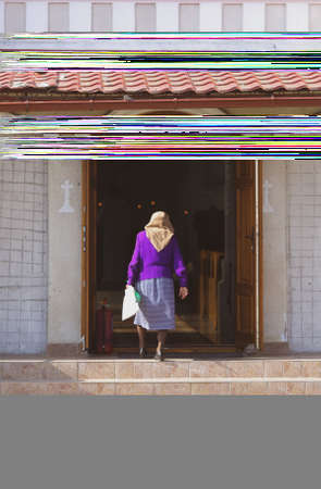 An old lady enters an christian orthodox church in a village in rural Romaniaのeditorial素材