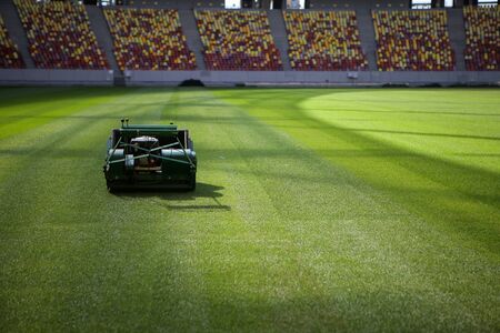 Industrial lawn mower machine on a soccer stadium with freshly installed and trimmed new turfの写真素材