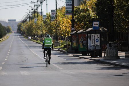 Bucharest, Romania - September 22, 2019: UBER Eats delivery biker on an empty boulevard during a sunny day.のeditorial素材