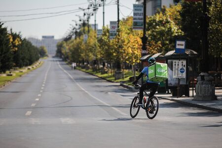 Bucharest, Romania - September 22, 2019: UBER Eats delivery biker on an empty boulevard during a sunny day.のeditorial素材