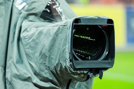 Details of a professional television camera, with rain cover, live broadcasting a soccer game.の写真素材